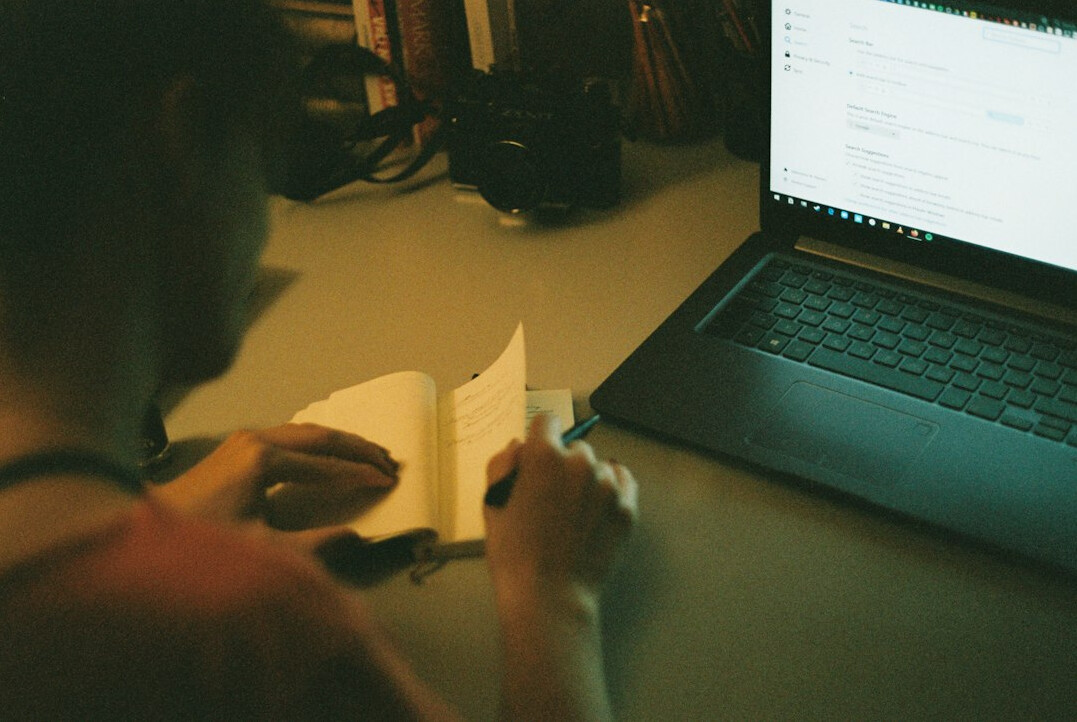 student taking notes while coding